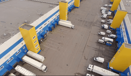 Image shows a traditional distribution network from above including warehousing fascilities and lorries loading