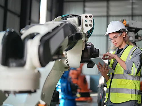 Comsim harness the power of digital - Lady in hard hat uses tablet to control a manufacturing robot