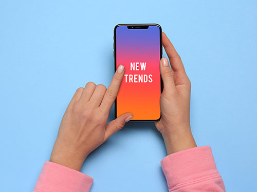 New trends. Woman using smartphone on blue background, top view