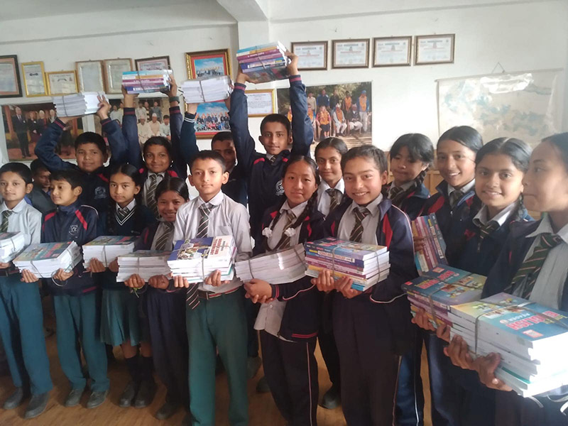 Classroom of Q. Learning Nepal students holding piles of books provided by the organisation